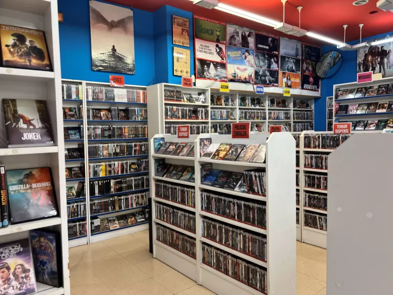 Vista general del videoclub con estanterías llenas de películas y carteles en las paredes